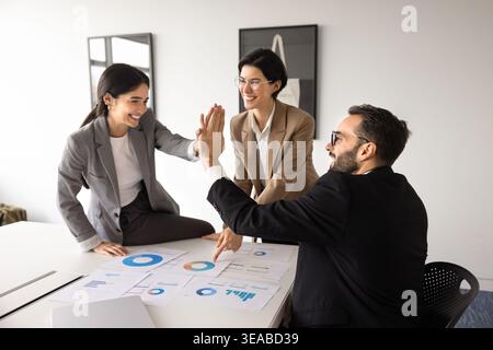 Diverse team celebrates project success with high five in office Stock Photo