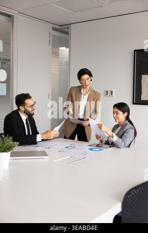 Business team reviewing printed reports and financial charts in boardroom Stock Photo