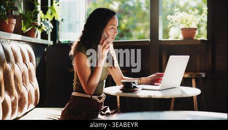 Woman, laptop and cafe with phone call for discussion, communication or conversation. Female person, freelancer or journalist talking with mobile Stock Photo