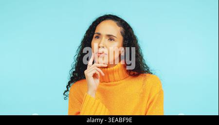 Thinking, vision and question with woman in studio for problem solving, reflection and future. Planning, idea and perspective with person on blue Stock Photo