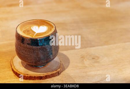 Side view of hot latte art heart in dark glazed ceramic cup on wood coaster. Japanese minimalist cafe style with large wooden copy space. Keywords (46 Stock Photo