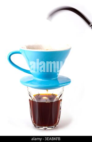 Professional manual drip coffee brewing with blue ceramic V60 dripper. Pouring hot water over coffee on white background. Stock Photo