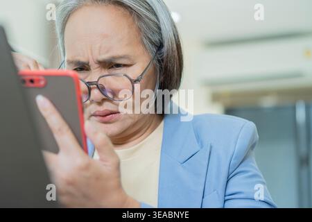 Woman, glasses and vision problem with mobile for contact, planning and difficulty reading in office. Depressed mature businesswoman holding phone at Stock Photo
