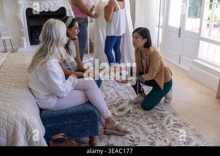 Diverse female friends and family including senior relative and bride-to-be choosing heeled sandals Stock Photo