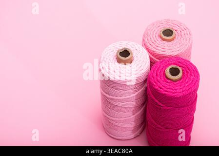 Three spools of thread in various shades of pink, arranged on a light pink background. Stock Photo