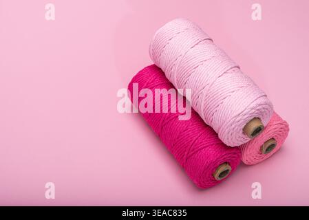 Three spools of thread in various shades of pink, arranged on a light pink background. Stock Photo