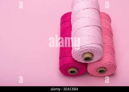 Three spools of thread in various shades of pink, arranged on a light pink background. Stock Photo
