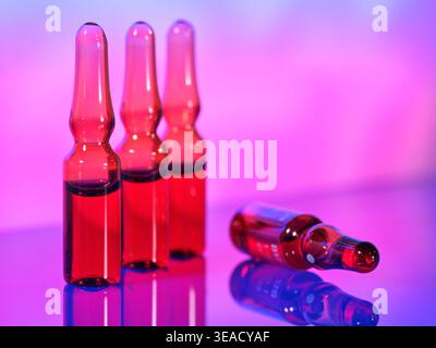 Three clear bottles with red liquid in a colorful setting around evening time Stock Photo