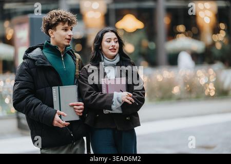 High school friends walking together outdoors holding college notebooks and talking in city Stock Photo