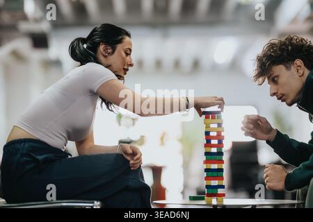 Two students concentrating while playing a block stacking game in a casual lounge Stock Photo