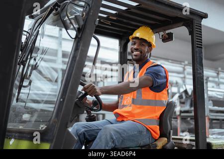 Portrait of a worker operator in a metal warehouse wearing personal protective gear sits in a forklift to transport and load heavy materials. Stock Photo