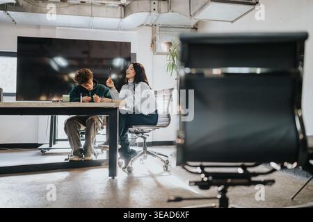 Two high school friends studying and collaborating at a modern office table in a bright meeting space Stock Photo