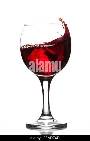 Wineglass with wine red juice beverage splashing wave and ice cube isolated on white background full size Stock Photo