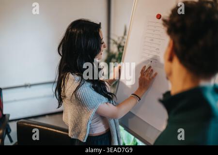 Two students collaborating at a whiteboard during a study session in a modern classroom Stock Photo