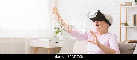 Modern senior woman using VR glasses at home Stock Photo