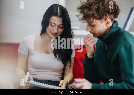 Two students studying together at home, collaborating on notes and learning in a casual setting Stock Photo