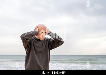 mature man standing with hands on head Stock Photo