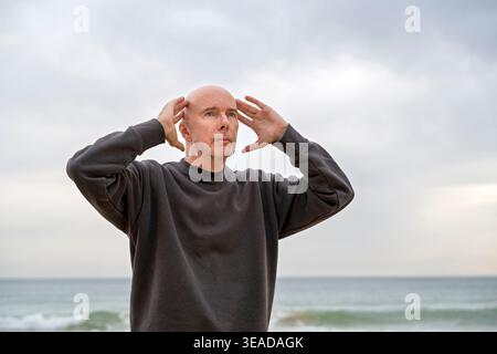 mature man standing with hands on head Stock Photo