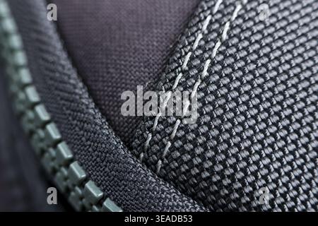 Close up macro detail black nylon fabric white double stitching metal zipper modern design sturdy structure durable material reliable construction qua Stock Photo