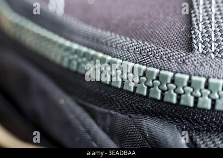 Macro close detail showing thick fabric textile texture with plastic teeth of an interlocking zipper designed to fasten and secure garment clothing cr Stock Photo