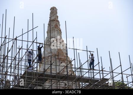 Workers carefully restoring ancient pagoda using metal scaffolding at Wat Phra Si historical park showing dedication to preserving cultural heritage s Stock Photo