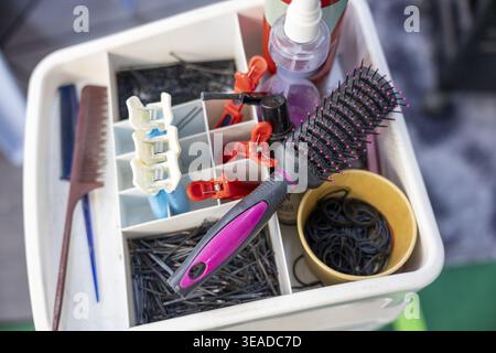 White plastic organizer tray holding salon hair styling tool collection including round brush comb clip pin spray bottle creating practical and ready Stock Photo
