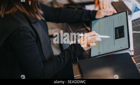 Business colleagues using tablet and stylus to review charts and data during an office meeting Stock Photo