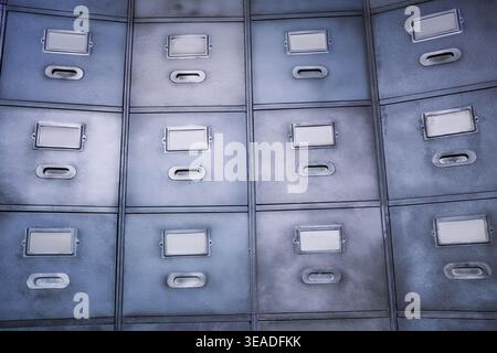 Metal filing cabinet drawers with empty label holders, suggesting organization, archives, storage, and bureaucracy in a vintage office setting Stock Photo