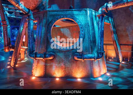13 January 2026, Dubai Expo City, UAE: Steampunk industrial interior design featuring metal plates, rivets, pipes, and a porthole, illuminated by blue Stock Photo