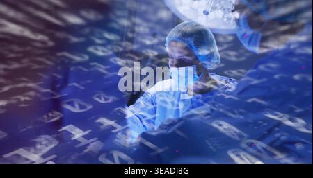 Operating lead surgeon gowned masked gloved bouffant capped in OR under lamp with data overlay Stock Photo