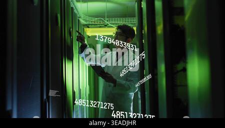 Inspecting Korean tech wearing white lab coat, pointing at server rack in data center with tablet Stock Photo