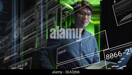 Monitoring IT engineer wearing dark shirt and glasses in data center racks, with laptop, copy space Stock Photo