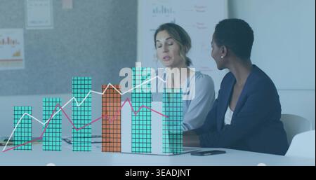 Discussing two colleagues reviewing overlay chart on laptop at table in light blouse dark blazer Stock Photo