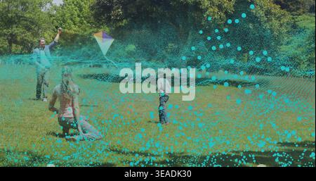 Holding man guiding multicolored kite, woman kneeling and boy running on lawn, turquoise overlay Stock Photo