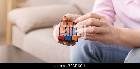 Hands Working on a Rubiks Cube in a Living Room With a Cozy Setting Stock Photo