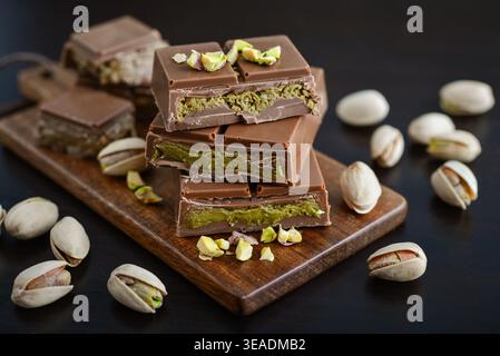 Dubai Chocolate bar with green kadayif and pistachio filling with pistachio nuts closeup on dark backgound Stock Photo