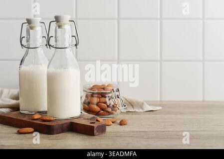 Almond milk in glass bottles with almond nuts on light background Stock Photo