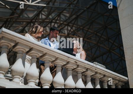 Young professionals collaborating on a laptop during an outdoor business meeting on a balcony Stock Photo