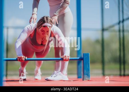 Outdoor fitness training with a female trainer assisting client doing bar push-up exercise Stock Photo