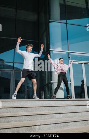 Young sportspeople exercising outdoors in front of modern glass building doing jumping jacks Stock Photo