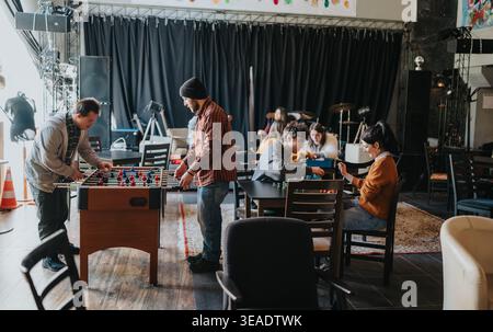 Students playing foosball and board games in a casual campus lounge with friends Stock Photo