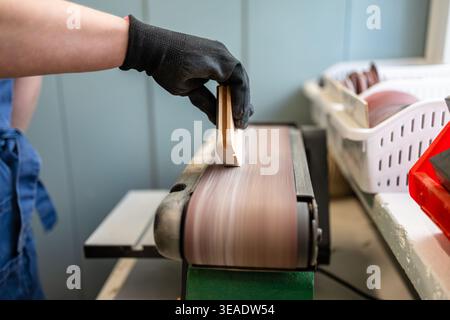 Woman’s Hands Guiding Wood Through Sanding Machine in Workshop Stock Photo