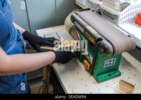 Woman’s Hands Guiding Wood Through Sanding Machine in Workshop Stock Photo