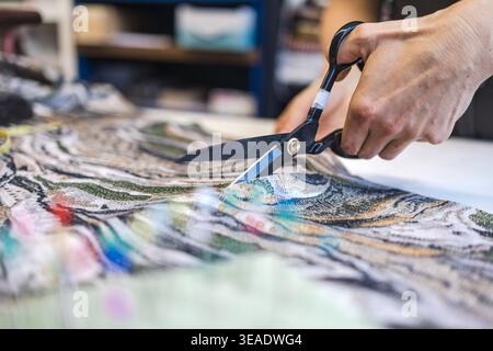 Cutting Fabric with Scissors on Worktable in Atelier Stock Photo