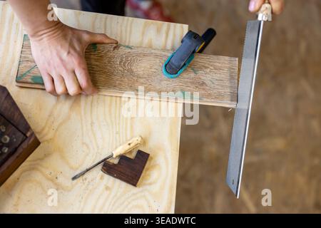Cutting Wood with Hand Saw on Workbench Stock Photo