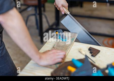 Cutting Wood with Hand Saw on Workbench Stock Photo