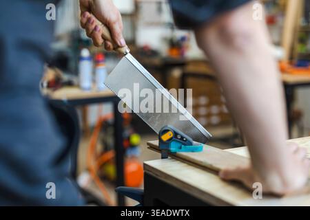 Cutting Wood with Hand Saw on Workbench Stock Photo