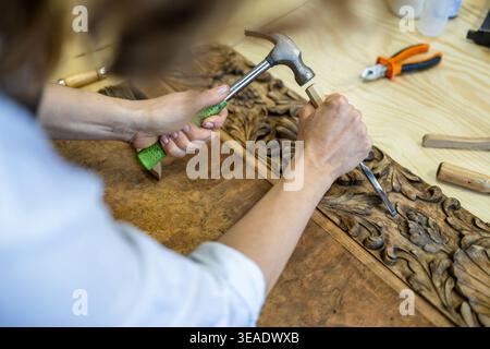 Restoring Ornate Wooden Panel with Carving Tools Stock Photo