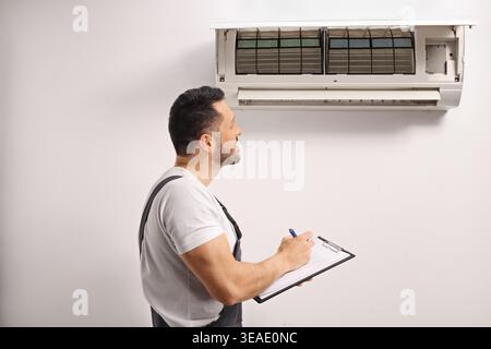 Air conditioner maintenance technician inspecting an indoor unit Stock Photo