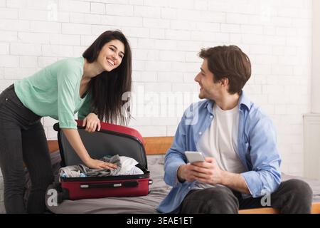 Couple Preparing for a Trip While Packing Suitcase in a Cozy Bedroom Setting Stock Photo